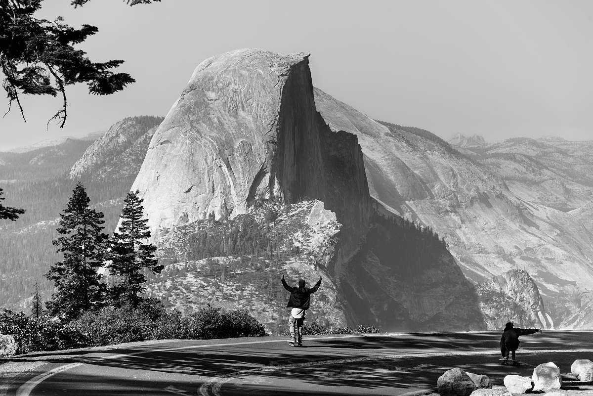 black-and-white grayscale photo of man standing on asphalt road fornt of mountain grey