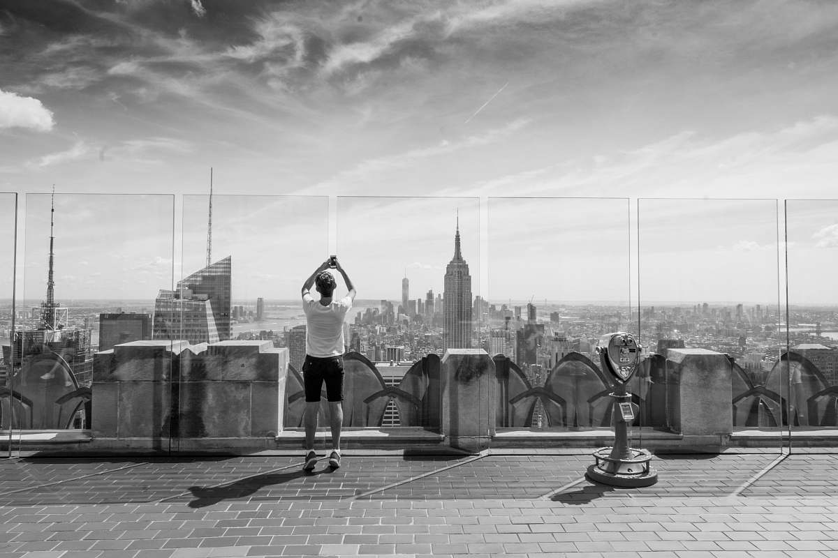 grey grayscale photography of man standing near tower viewer black-and-white