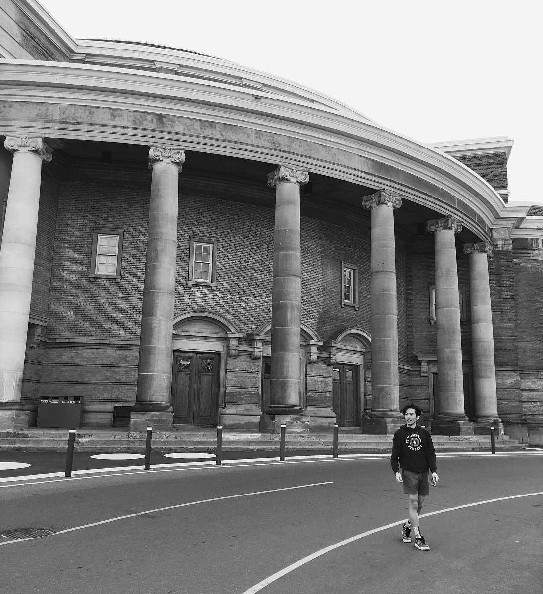 person grayscale photography of man walking beside building black-and-white