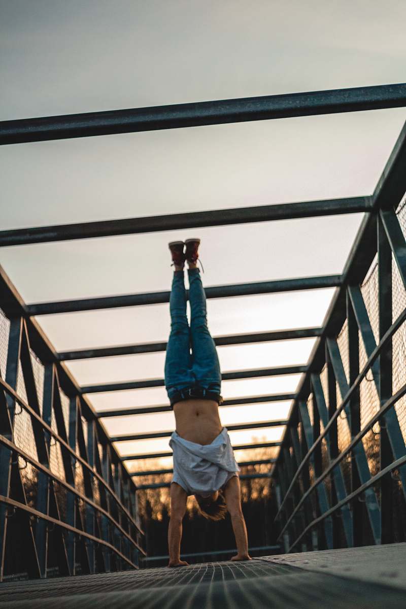 Experience the thrill of acrobatics with this striking image of a man performing a handstand on a bridge. This captivating scene showcases not only remarkable athleticism but also the beauty of urban landscapes. Ideal for fitness, sports, and inspirational themes, this image can be used in promotional materials, blogs, and social media posts that celebrate physical challenges and the art of movement.