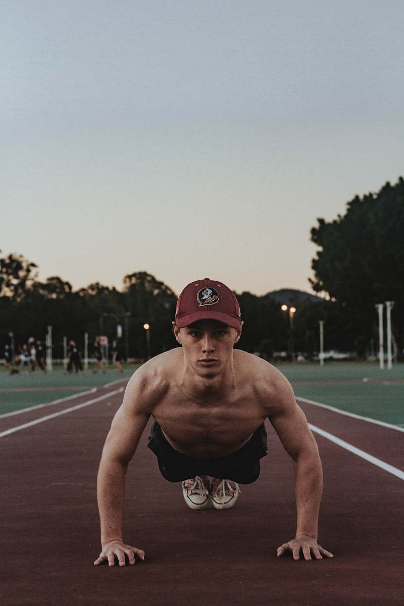 person man doing push up on field running track