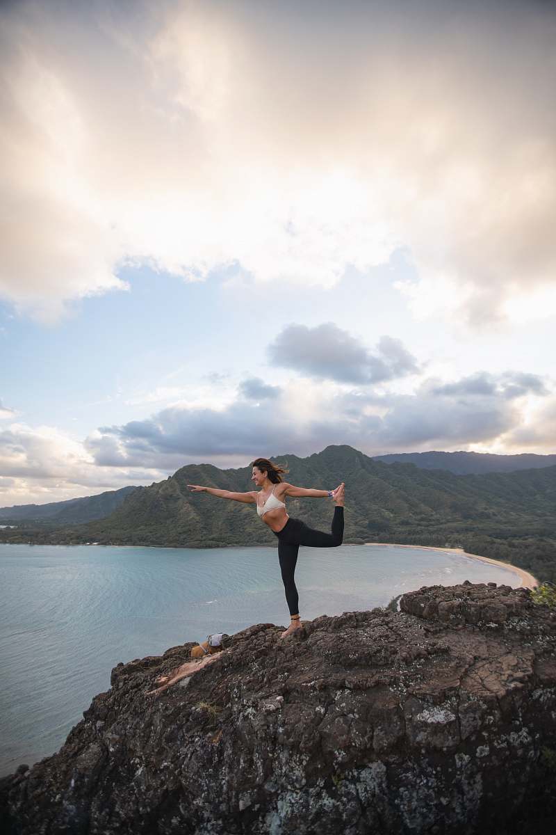 person man doing yoga on rock formation outdoors