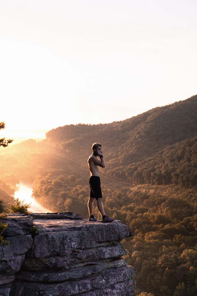 people man in black shorts standing on cliff during golden hour person