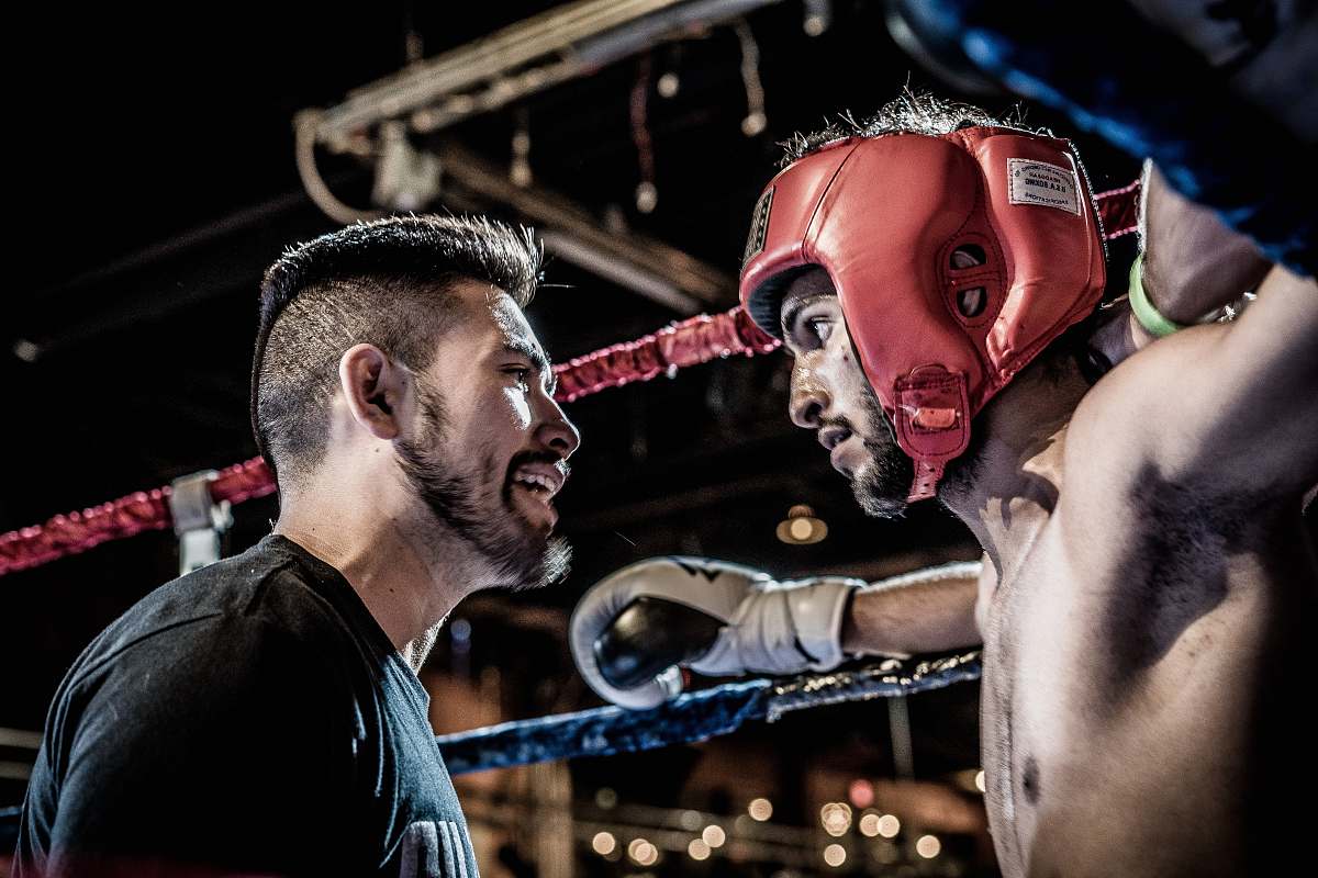 person man in black talking to boxer inside ring people