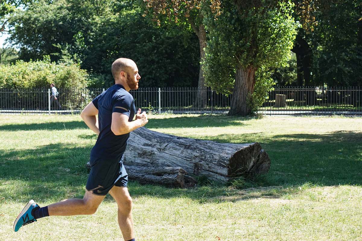 person man in blue t-shirt and blue shorts running near log shorts