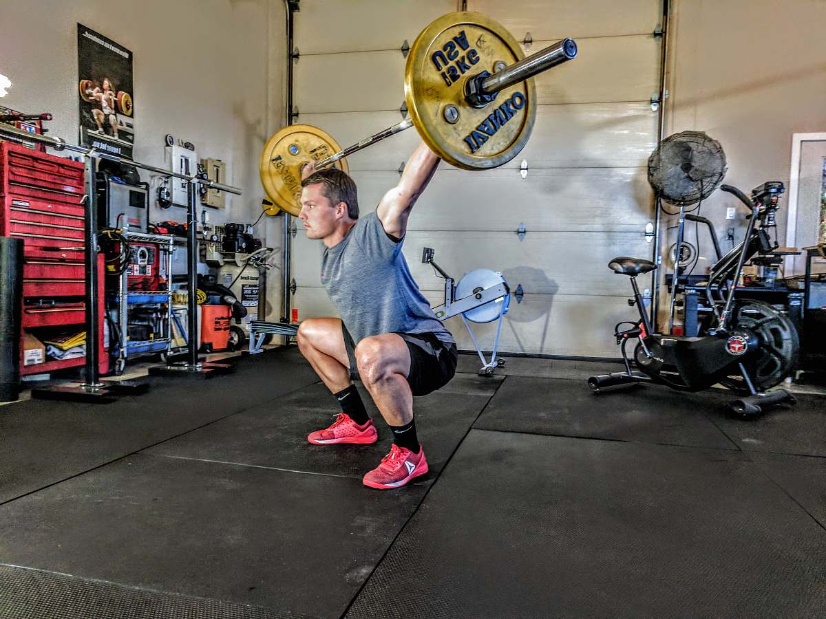 people man in gray t-shirt lifting gray and yellow barbell person