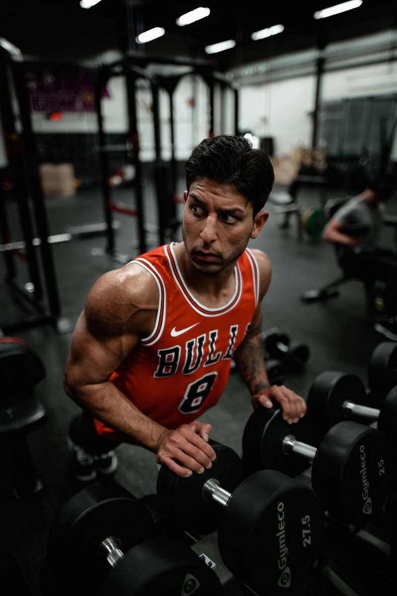 person man in red Chicago Bulls jersey doing push-up exercise on dumbbells sports