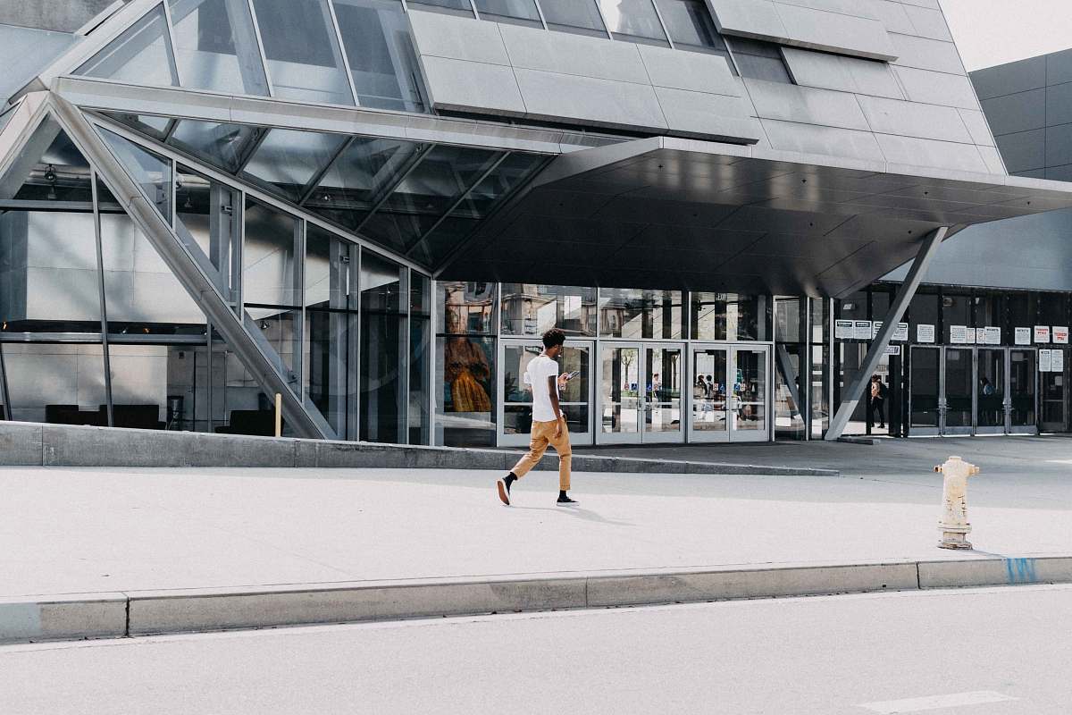 person man in white t-shirt walking beside building during daytime architecture