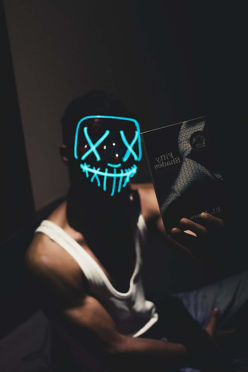 person man in white tank top holding Fifty Shades book light