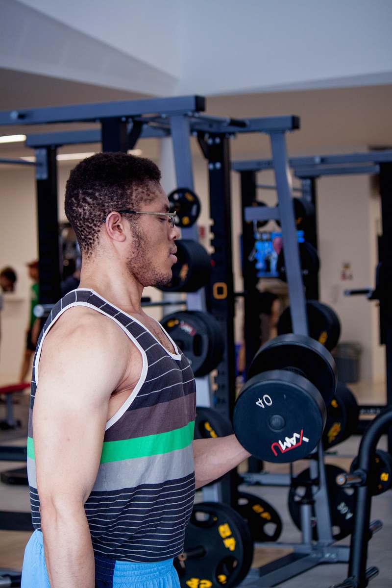 people man lifting 40 LBS. dumbbell inside gym person