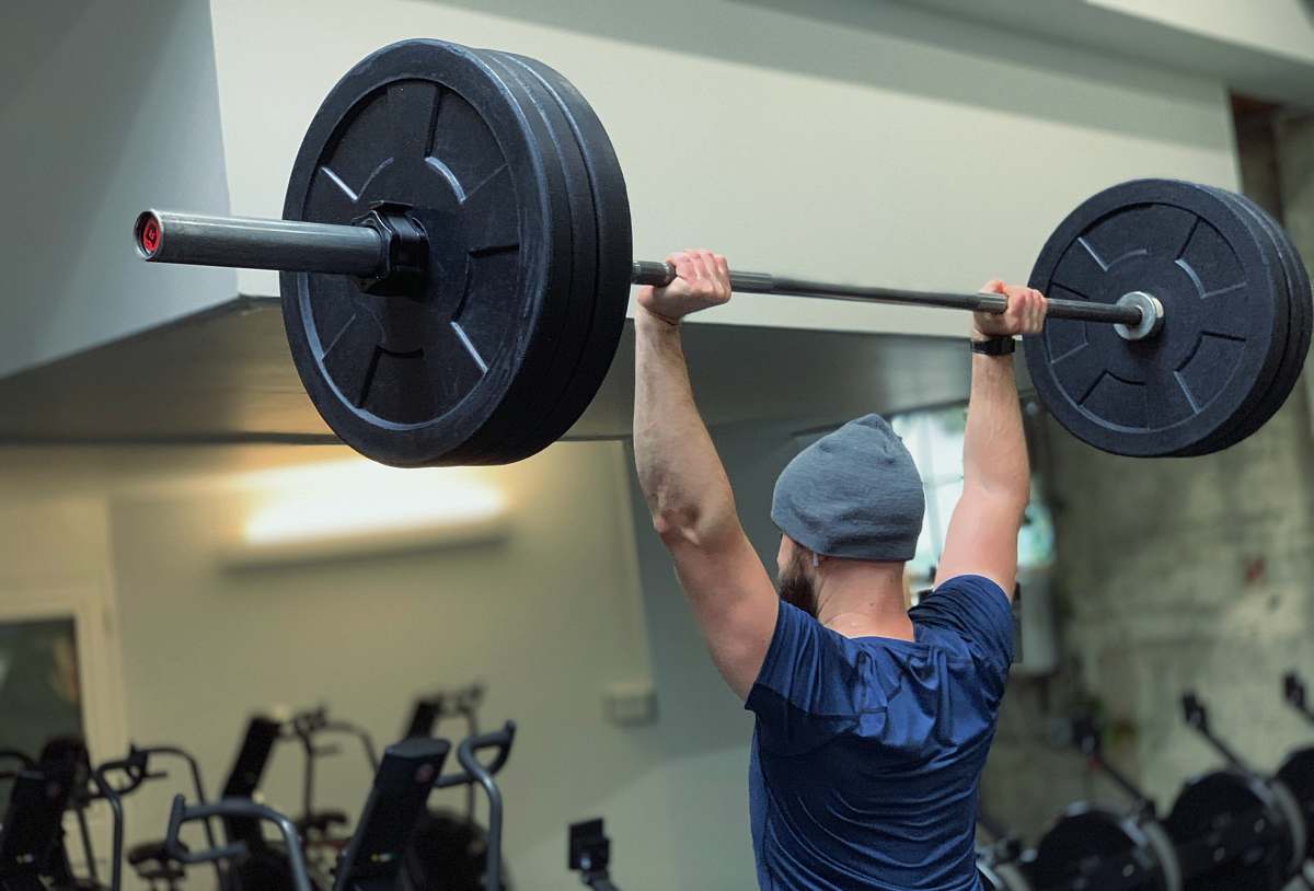 sports man lifting barbell in gym person