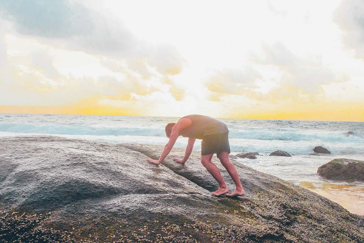 person man on gray rock near body of water water