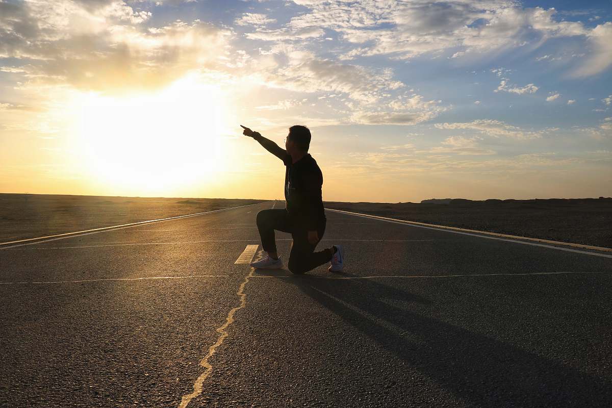 person man on road under clear blue sky asphalt