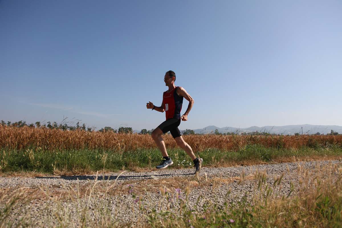 person man red and black top running on farm road sport