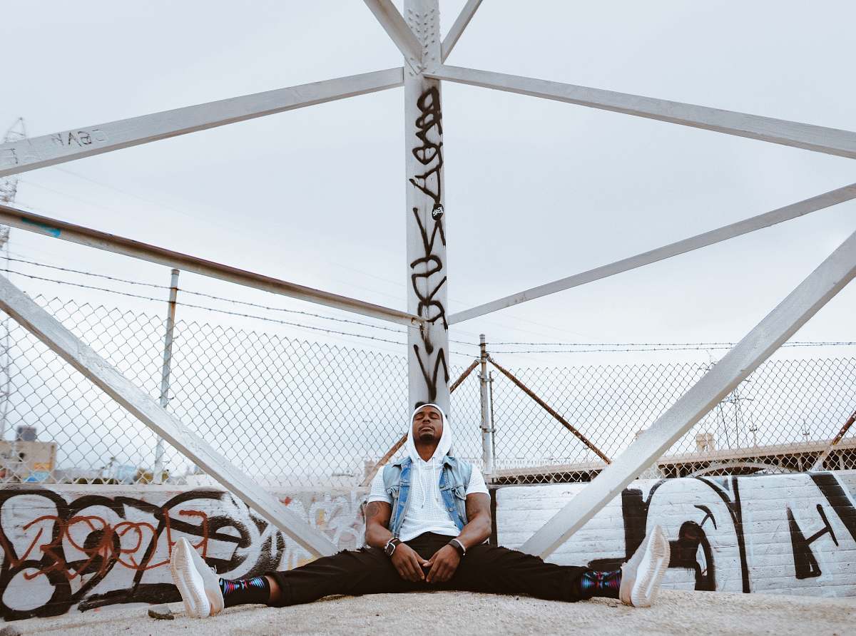 person man sitting beside white metal stand outdoors