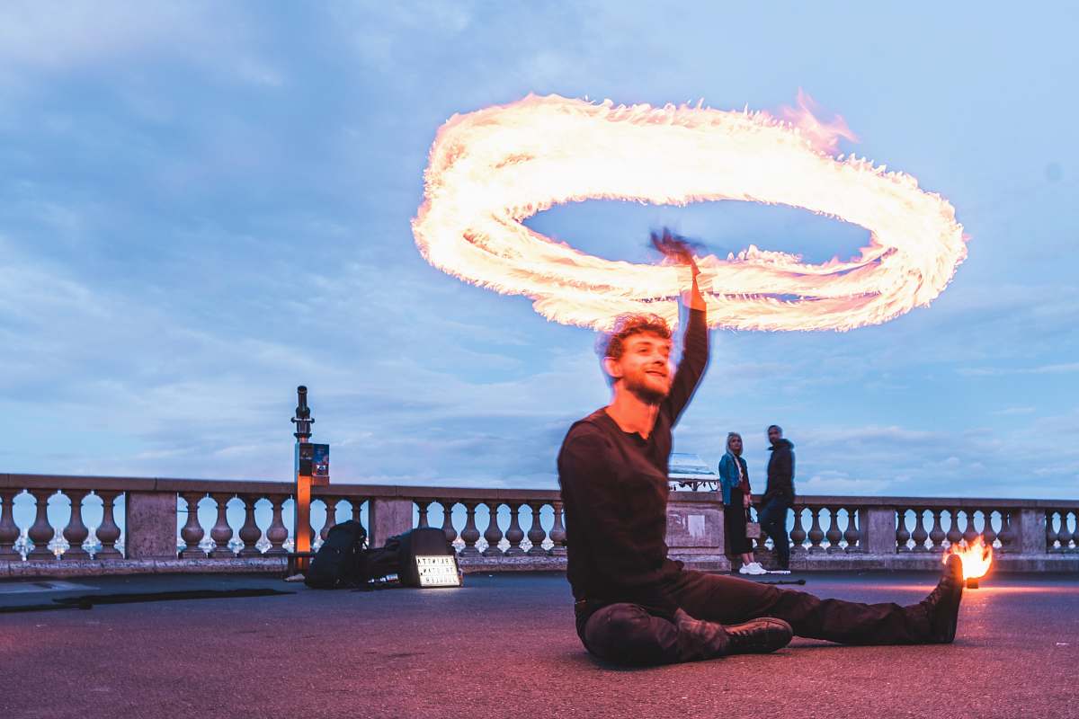 person man sitting on road whirling firecracker during daytime basílica del sacre coeur