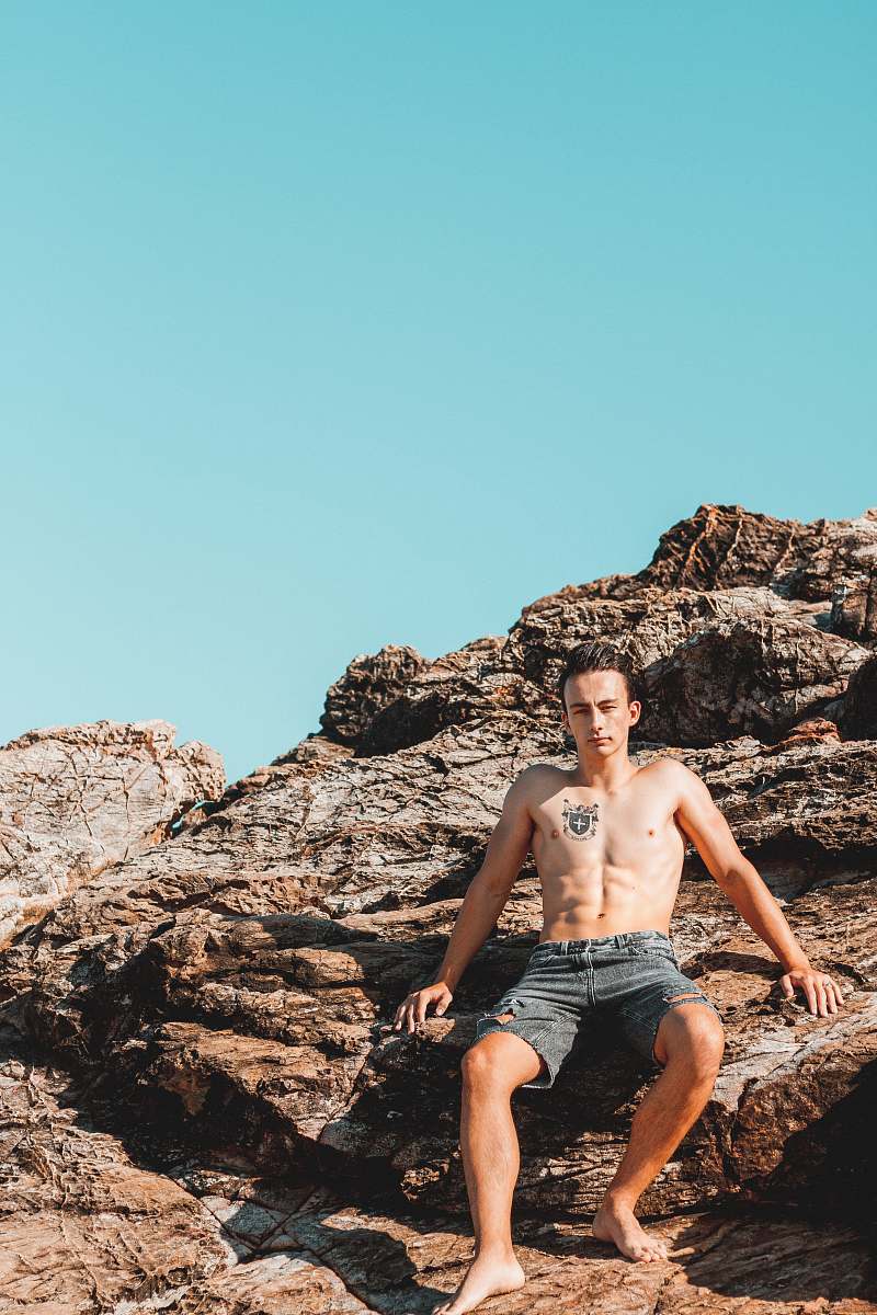 person man sitting on rock fragment during daytime people