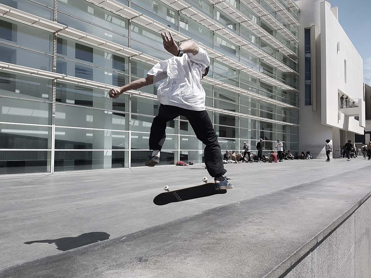 person man skateboarding beside building during daytime people