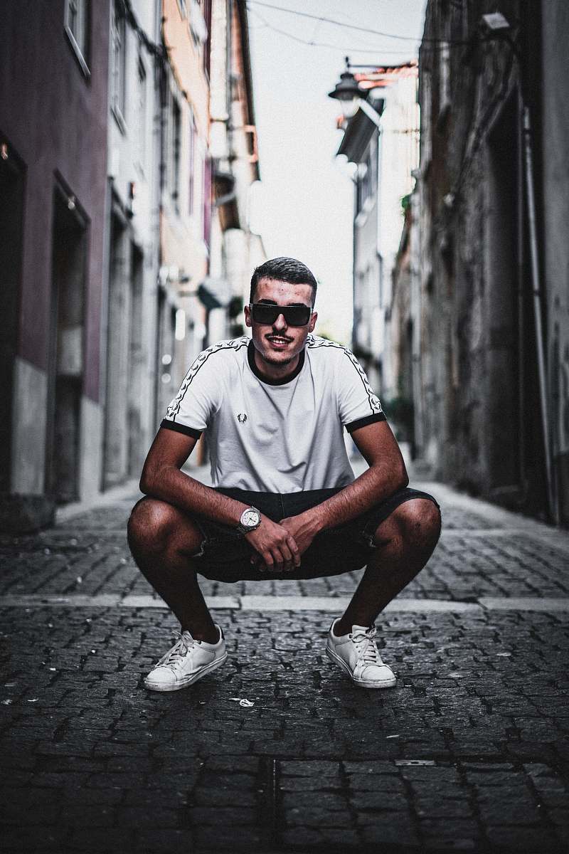 Capture a moment of reflection with this striking image of a man squatting and sitting on the ground in a narrow alleyway. This evocative scene conveys a sense of solitude and introspection, perfect for use in articles about urban life, mental health, and personal growth. The gritty backdrop enhances the emotional depth of the image, making it suitable for editorial pieces, social media posts, or visual storytelling projects.