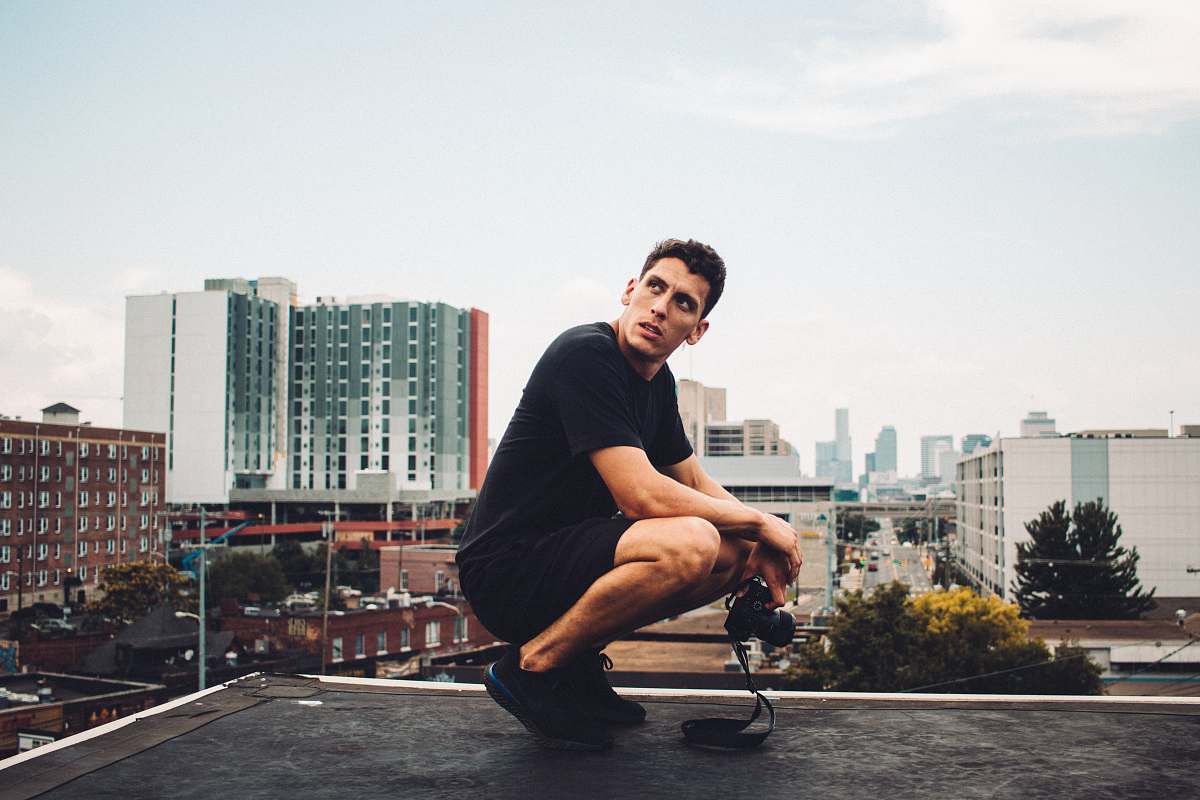 person man squatting on black building roof city