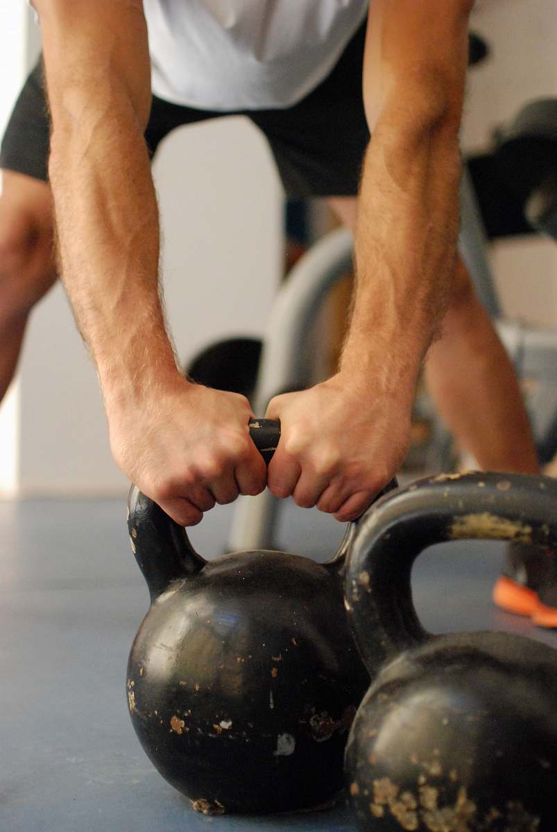 person man standing and holding kettle bell finger