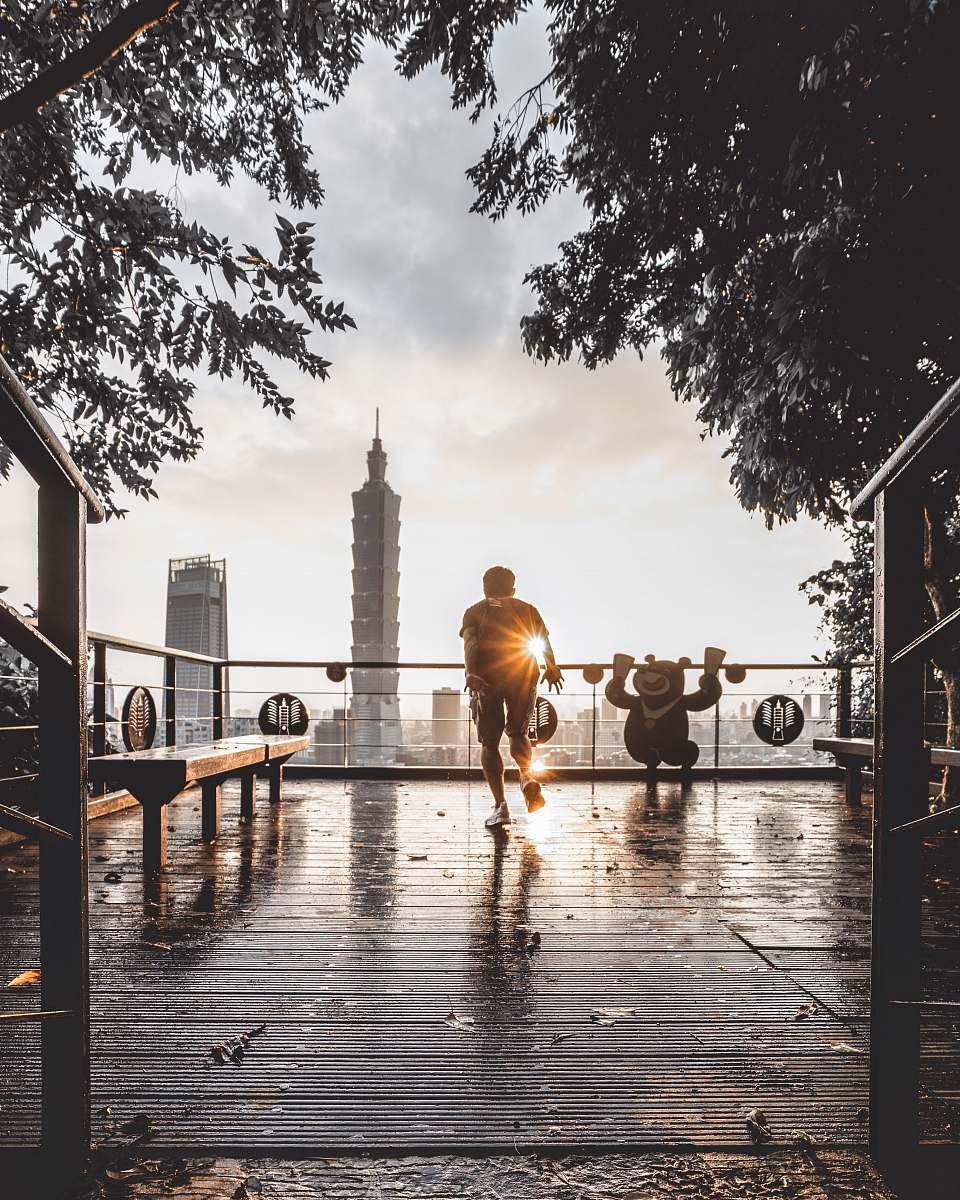 water man standing beside wooden bench across gray tower waterfront