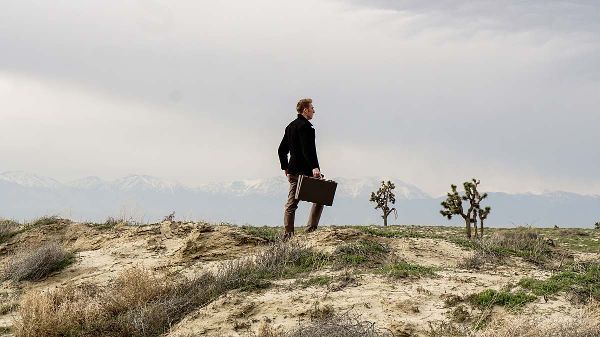 person man standing on brown field grass during daytime people