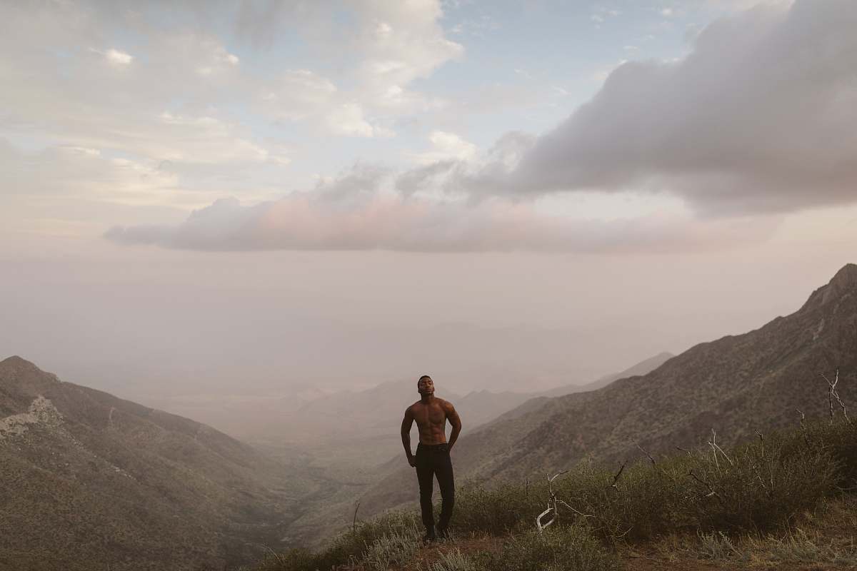 person man standing on mountain peak under white clouds people