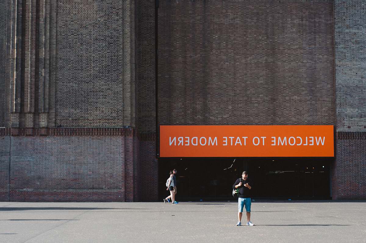 person man standing on pavement near building during daytime people