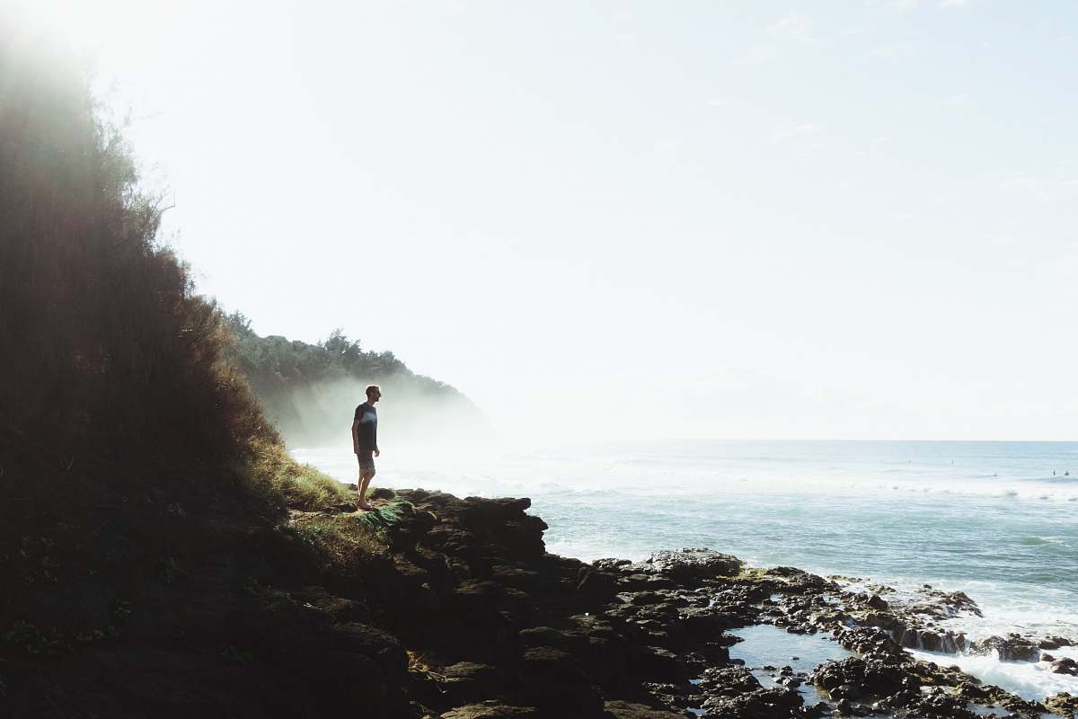 person man standing on rocky hill looking on sea sport
