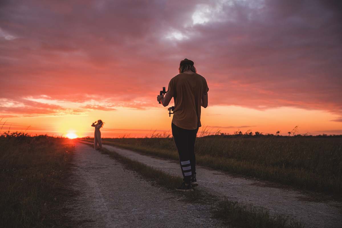 person man taking photo of woman during golden hour outdoors