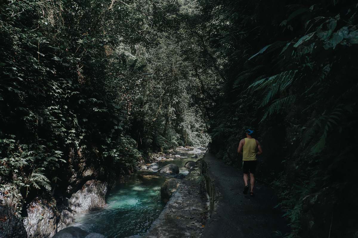person man walking beside river near mountain during daytime nature