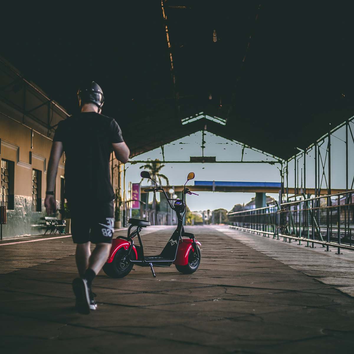 person man walking near red motor scooter bicycle