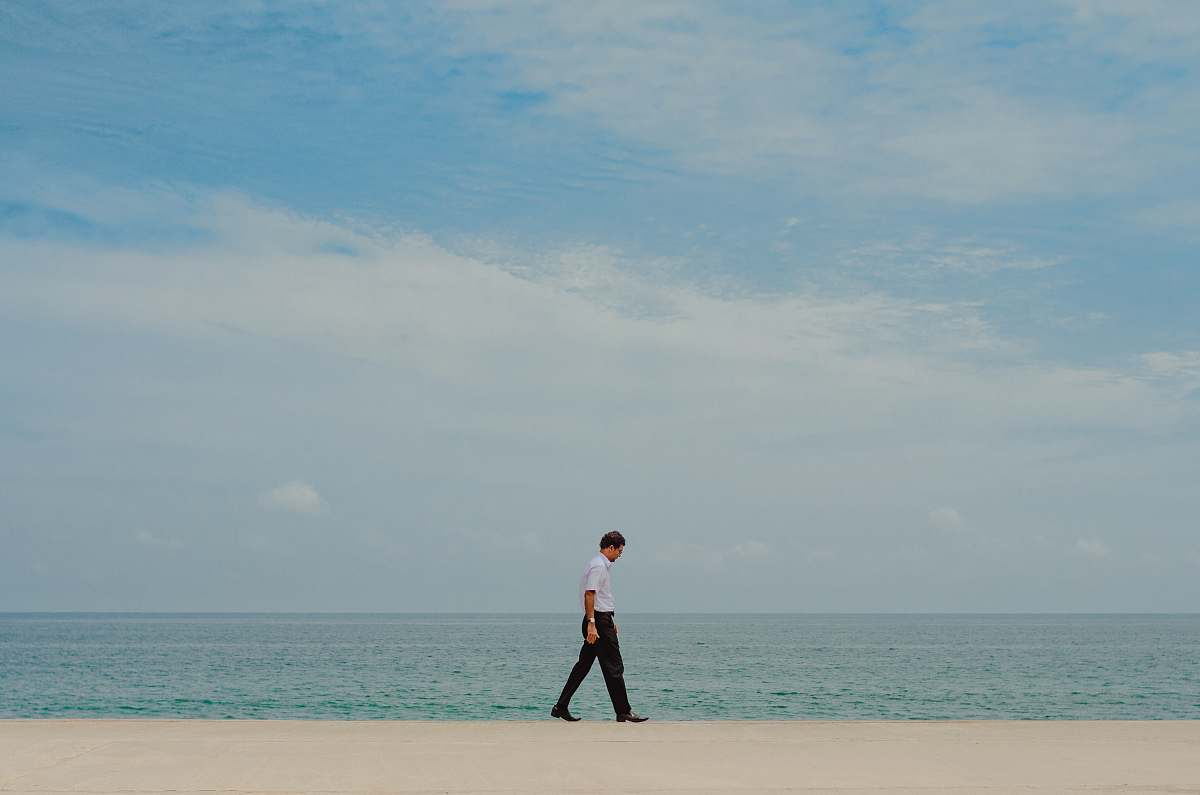 person man walking on shore near body of water standing