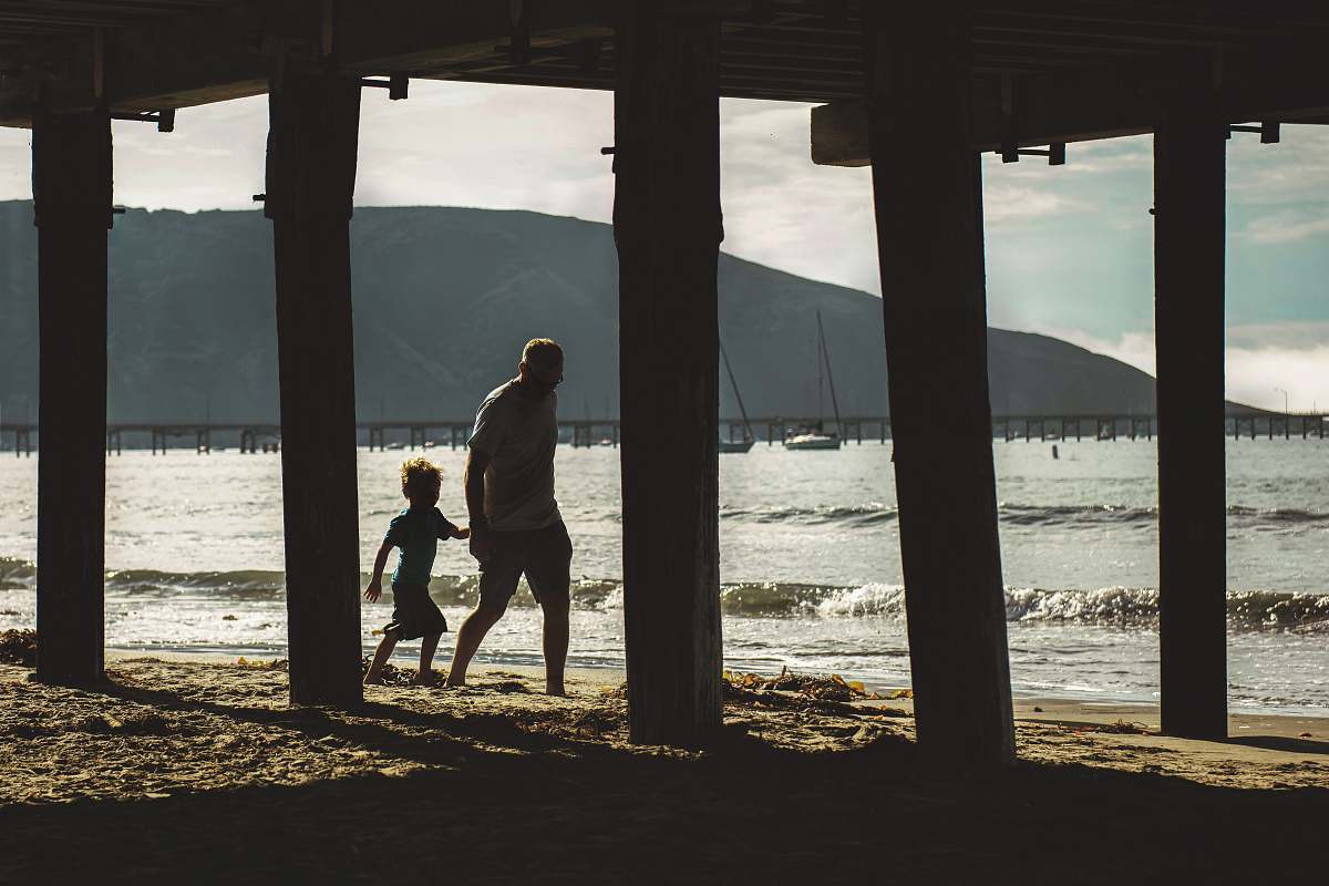 person man walking with boy on shore apparel