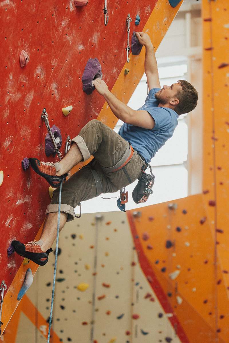 person man wall climbing on red wall climbing