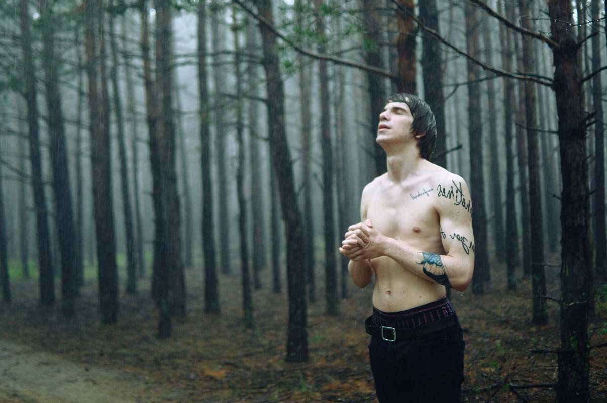 people man wearing black bottoms standing surrounded by tall trees during daytime person