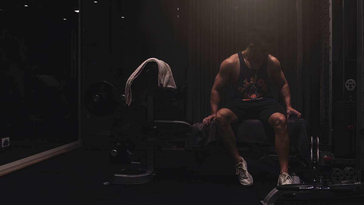 person man wearing black tank top sitting on the weight bench footwear