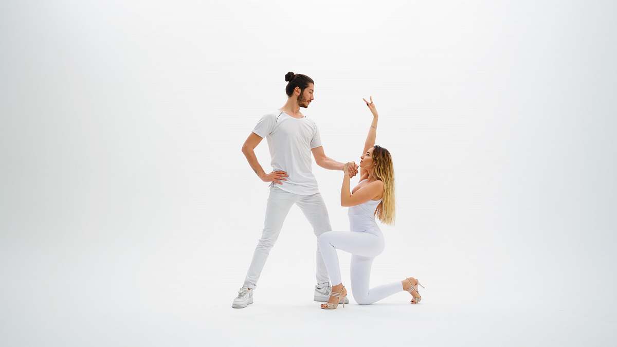 person man wearing white shirt holding hands with woman wearing white pants dance pose
