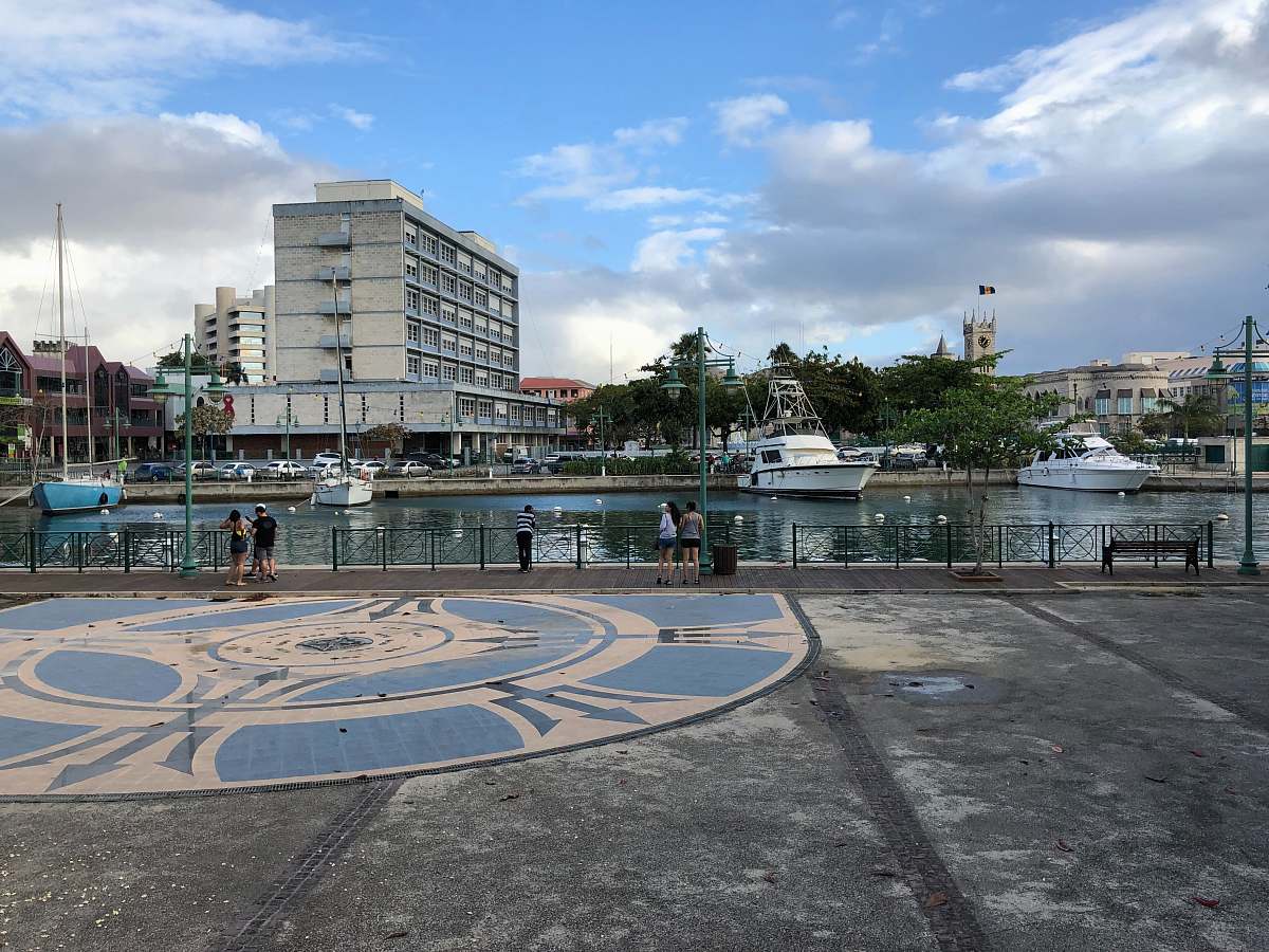 person people standing near lake viewing city with high-rise buildings under blue and white skies boat