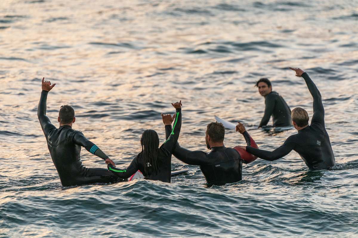 person people wearing black wetsuits in body of water people
