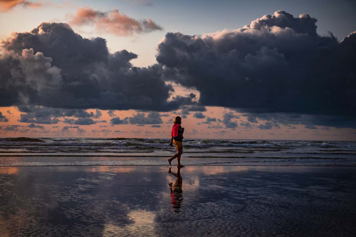person person walking beside seashore during daytime weather