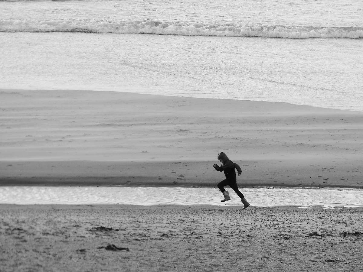 person running person on seashore during daytime black-and-white