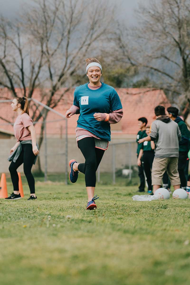 person selective focus photography of woman running on green lawn grass during dytime apparel