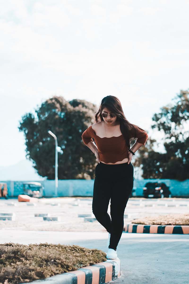 person selective focus photography of woman wearing brown off-shoulder blouse and black pants exercise