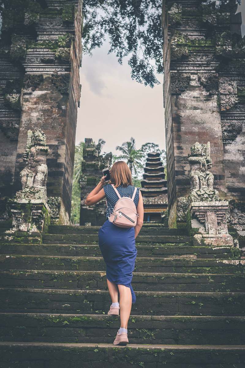 person shallow focus photography of woman in blue dress walking towards temple people