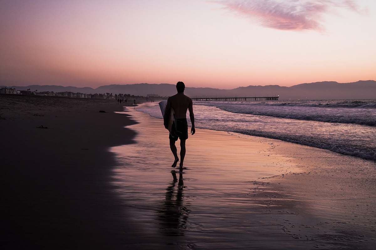 person silhouette of man walking along seashore people