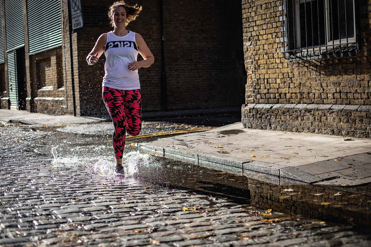 path smiling woman running in road with water walkway