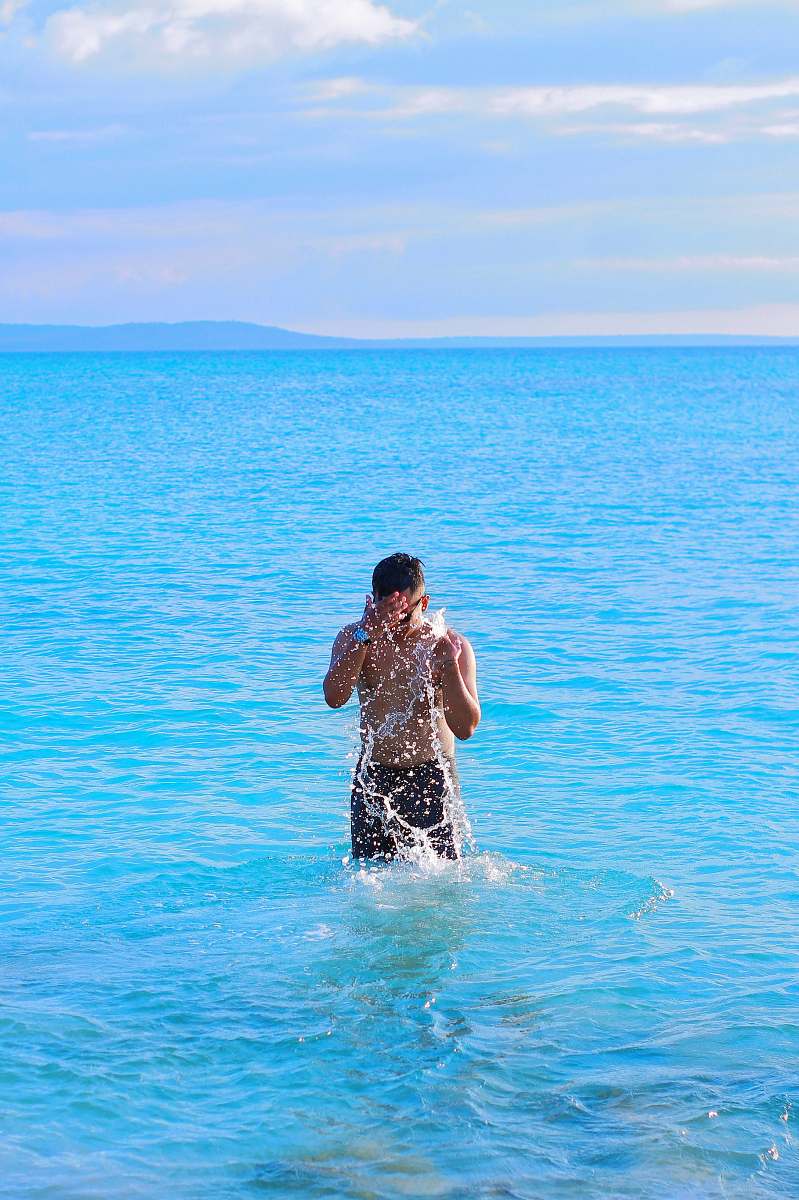 person time-lapse photography of man splashing water in blue sea apparel