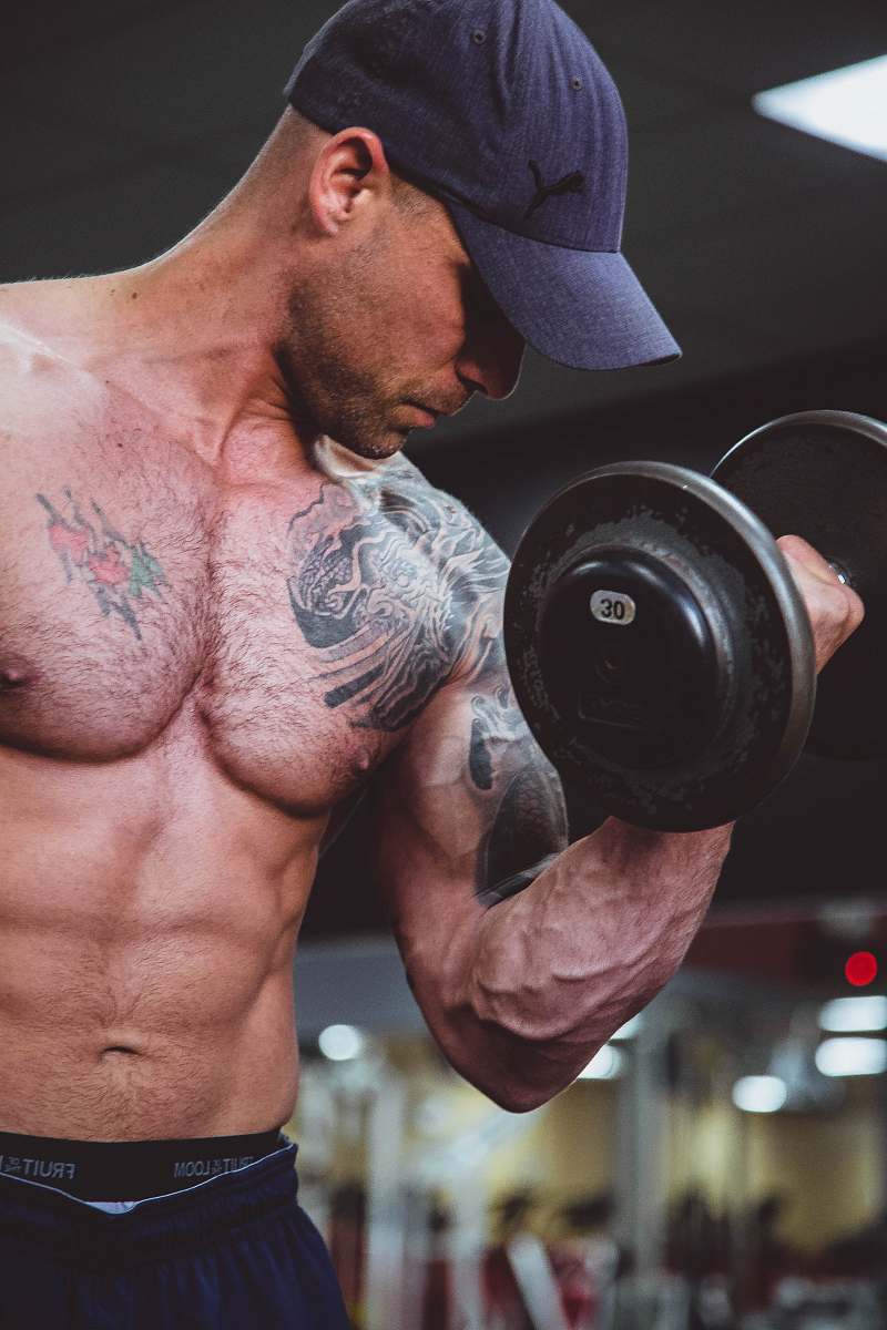 person topless man holding black dumbell on right hand people